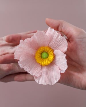 Anémone de Japon en papier positionnée sur deux mains entrelacées.